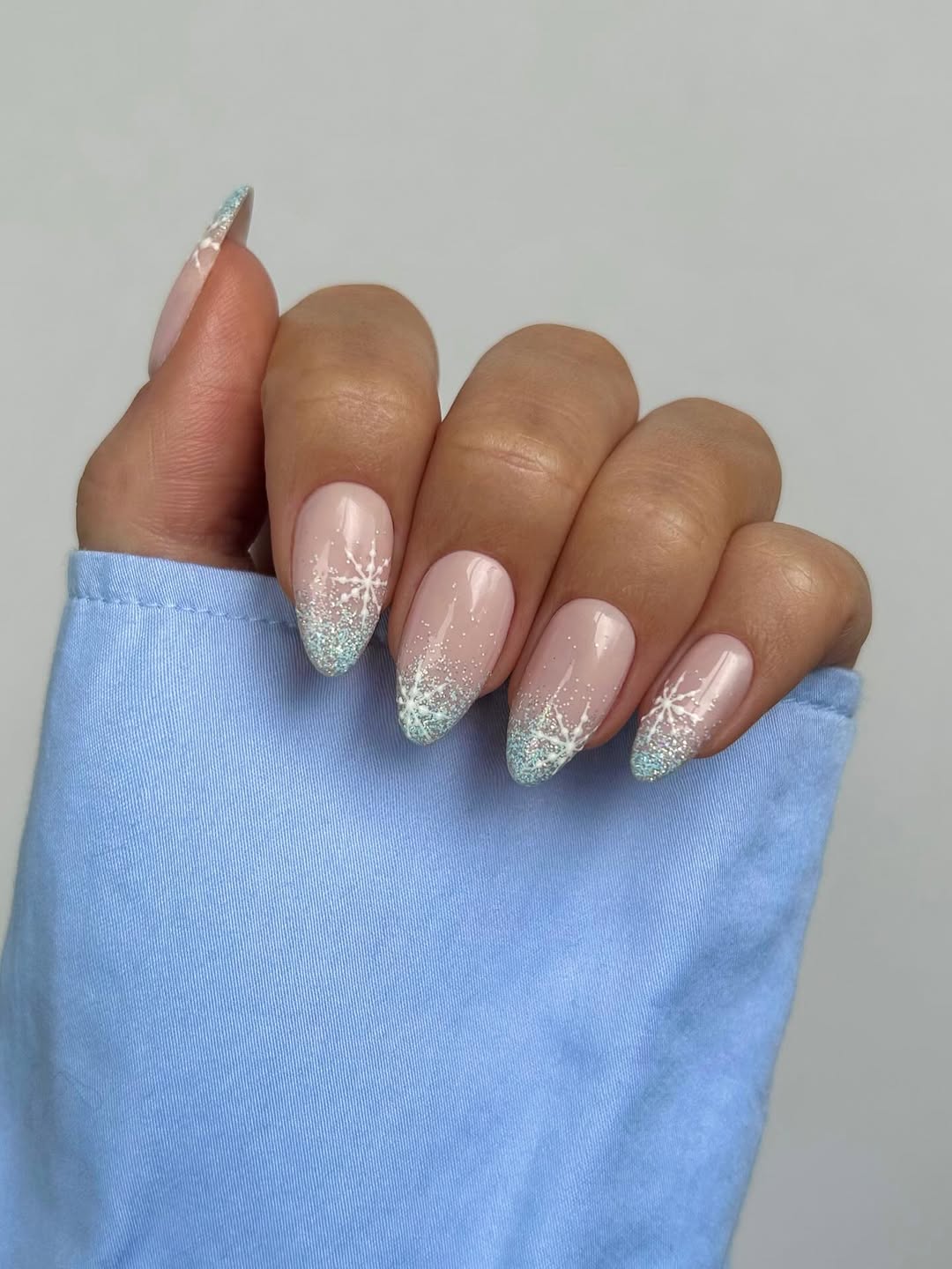Nude base with frosty blue glitter tips and delicate white snowflakes