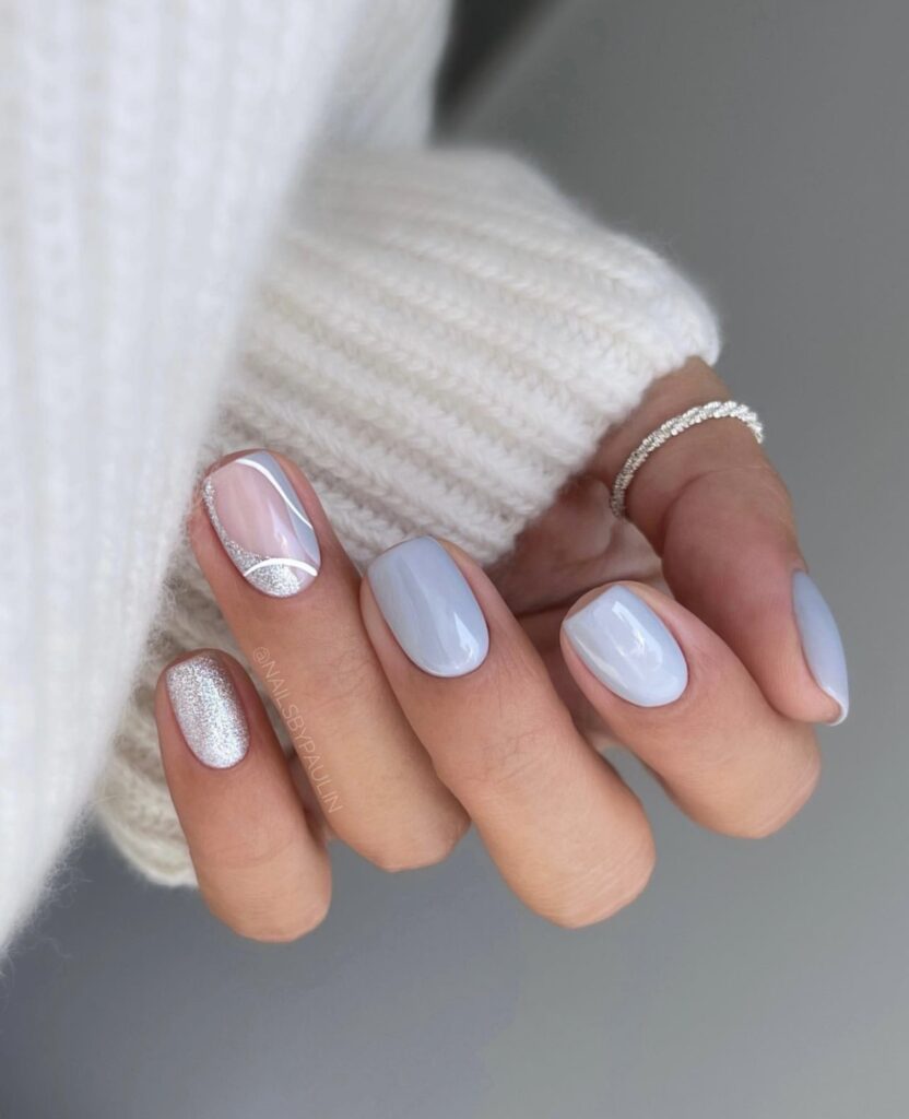 Short winter nails with a gradient effect from silver to light blue.