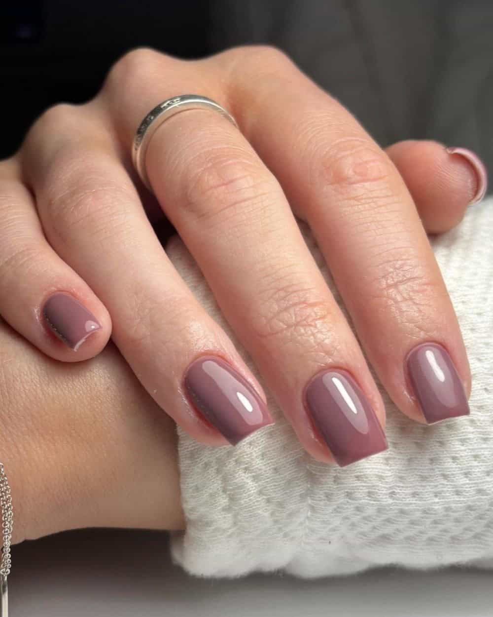 Short, rounded nails painted in a chic moody mauve