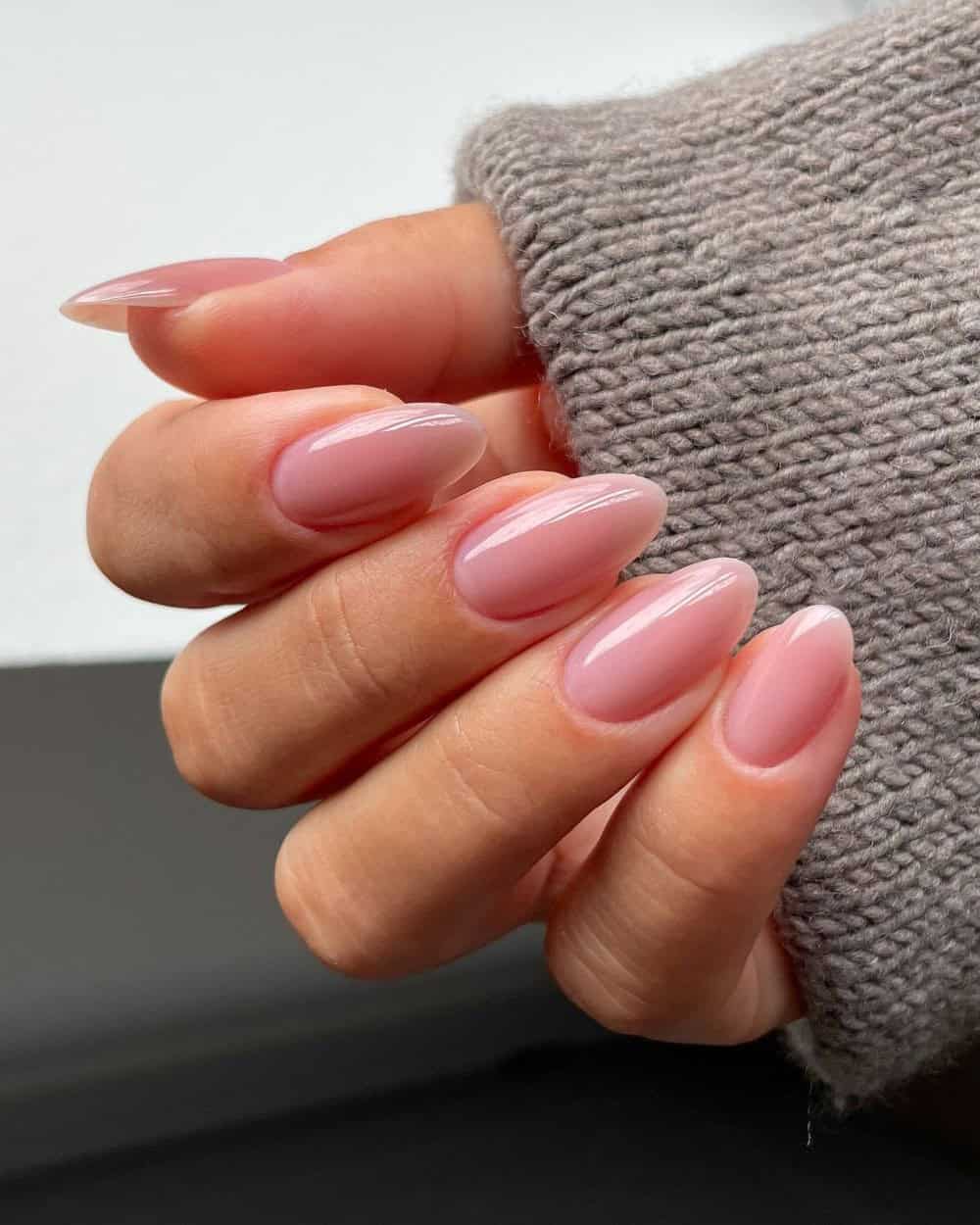 A close-up of sheer pink nails with delicate nail art