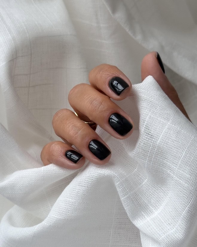 Glossy black nails with a sharp, modern shape