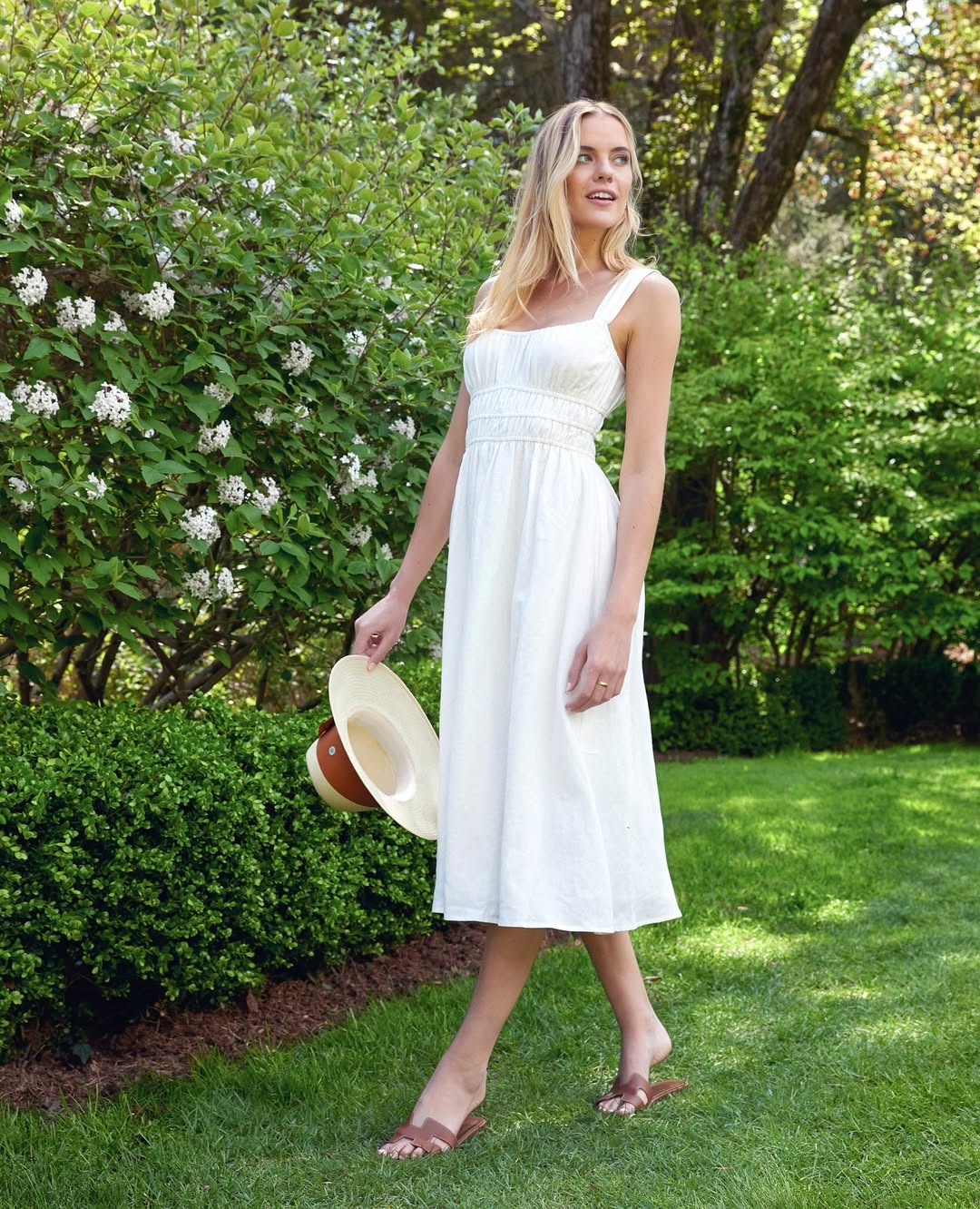 A woman in an embroidered top and jeans with loose waves.