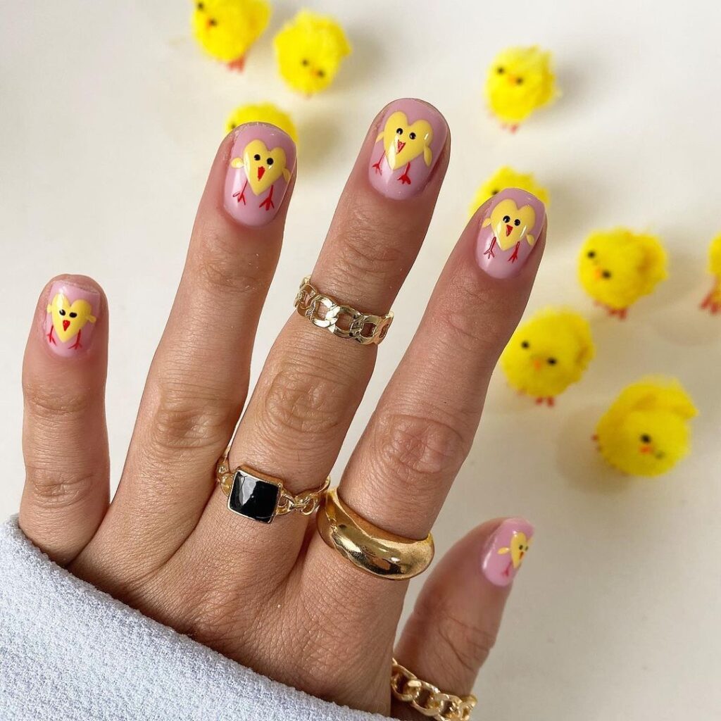 Pastel pink nails with cute yellow chick designs for Easter.
