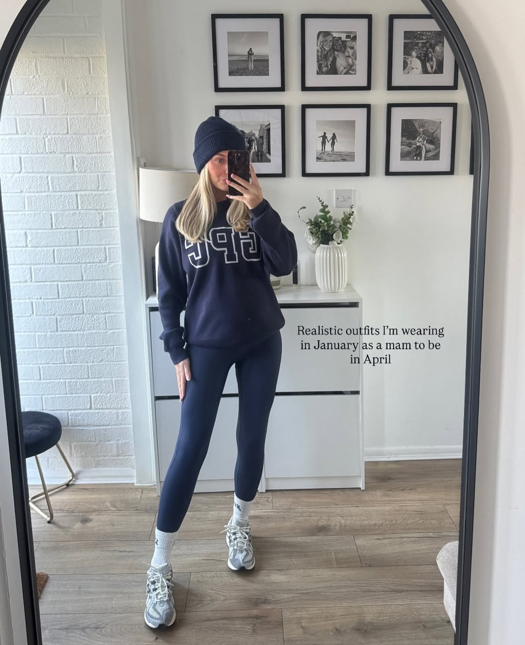 A woman in a comfortable, oversized winter maternity outfit including a sweatshirt and beanie.