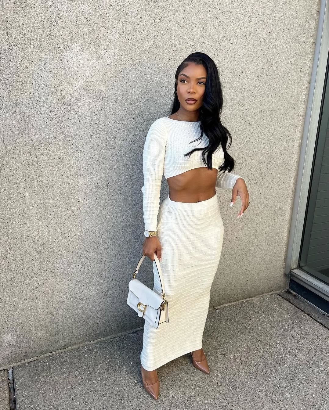 A woman in a ribbed cream-colored matching set with a subtle midriff cutout.