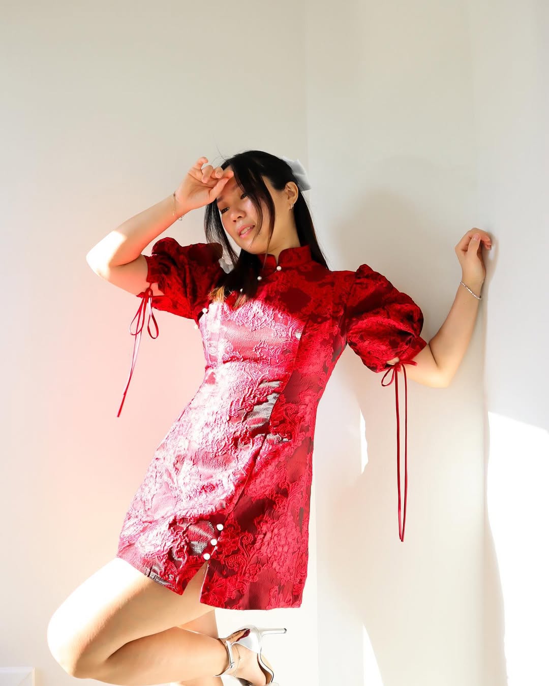 A woman in a short, bright red dress with structured sleeves, embodying a youthful and festive spirit for Lunar New Year.