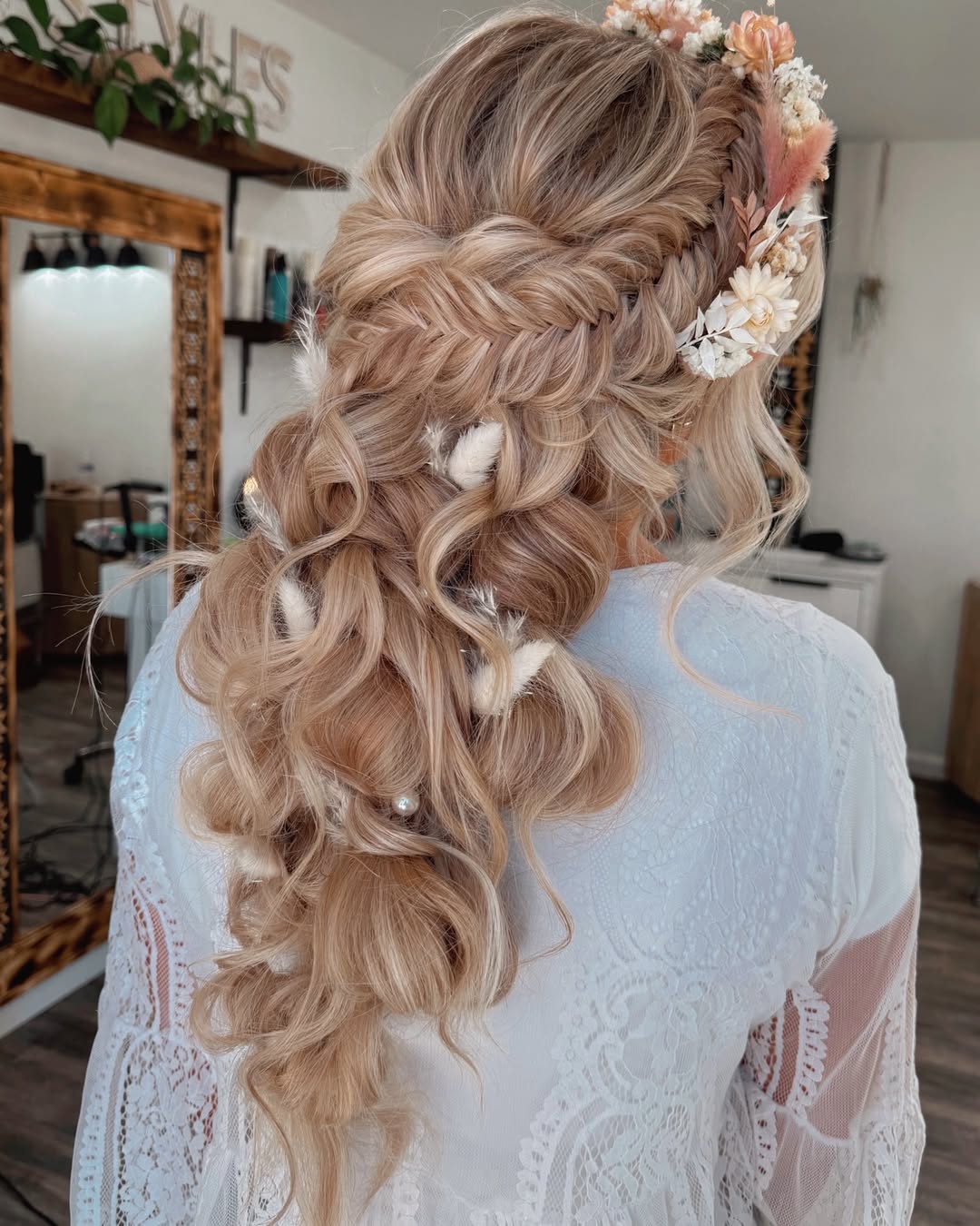 A braided updo adorned with flowers and soft curls.