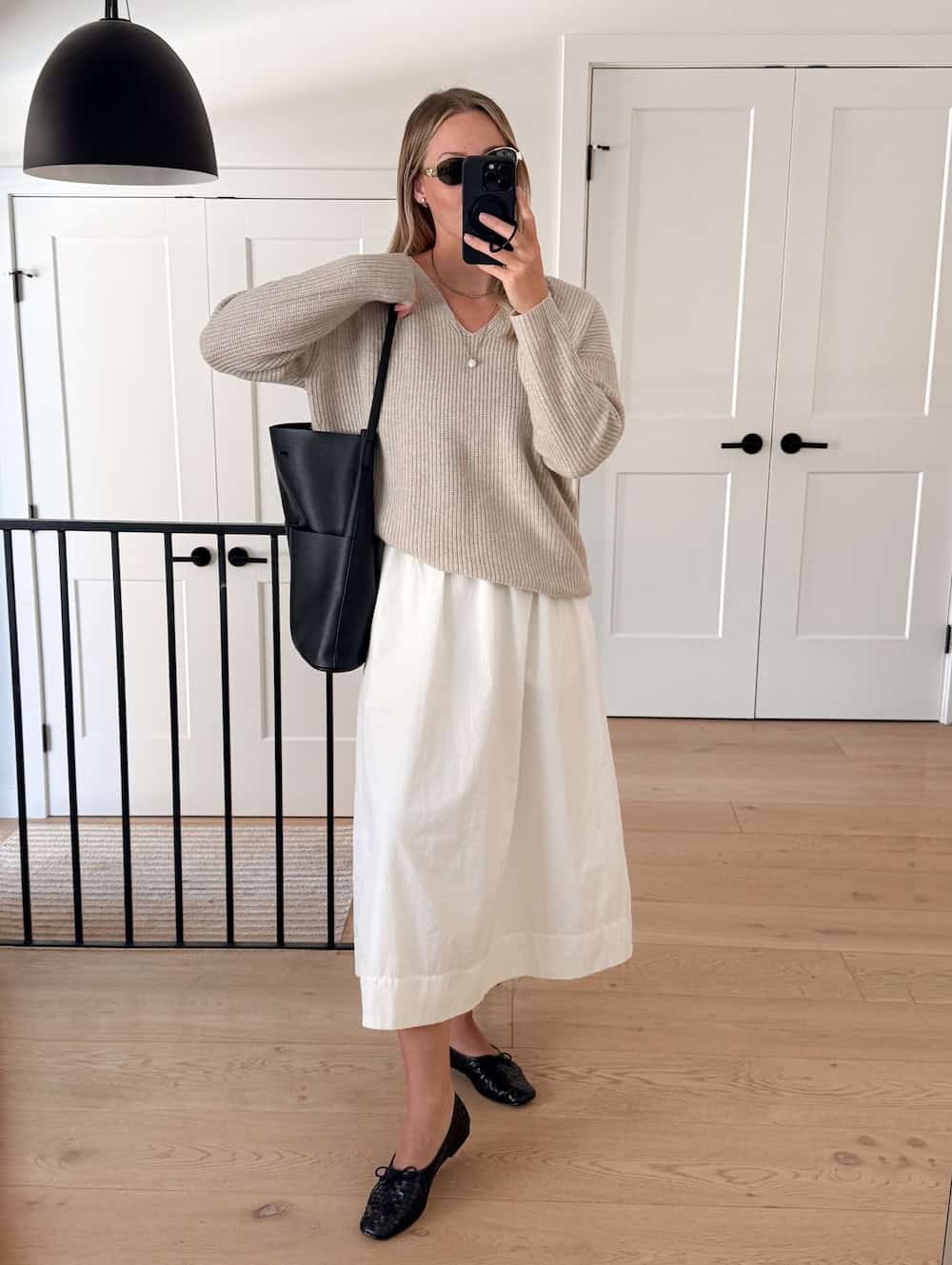 Woman wearing a poplin skirt, neutral sweater, and woven flats