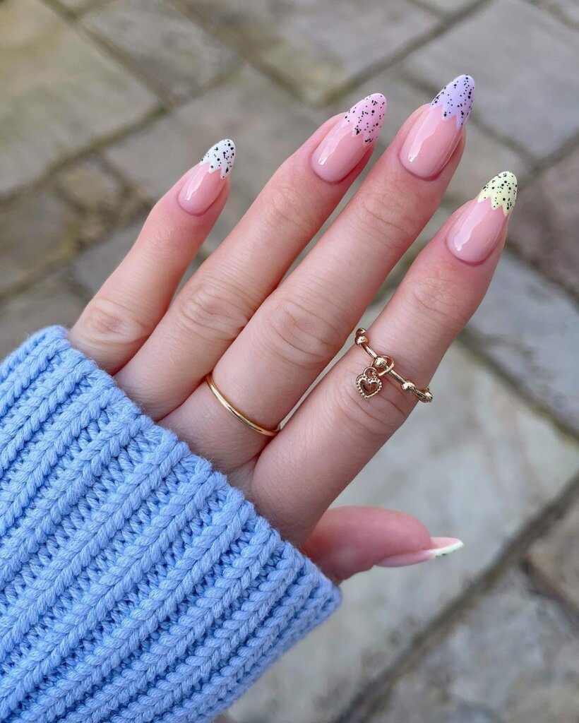 Almond-shaped nails with soft pink bases and delicate speckled tips.