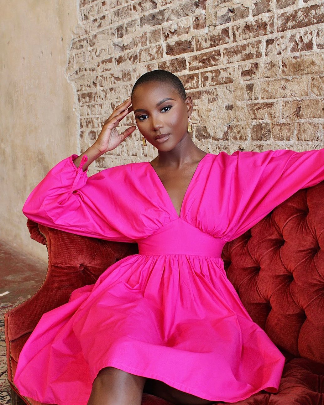 A woman in a bright pink dress with cinched waist and billowy sleeves.