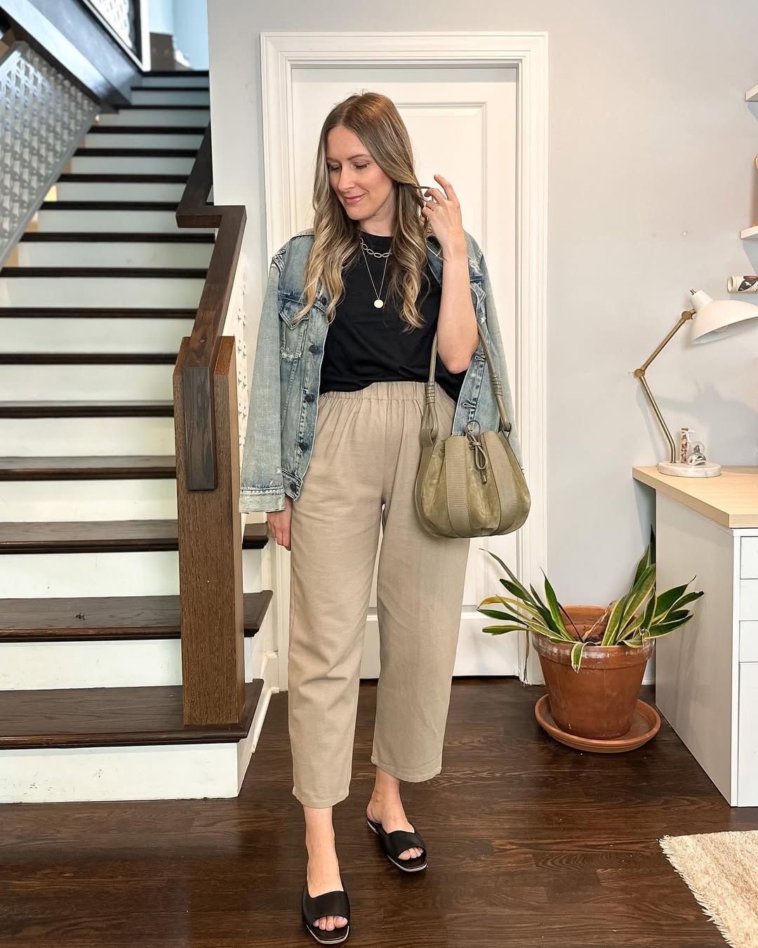 Soft beige trousers, a black tee, and a worn denim jacket create an unfussy, calm, and highly wearable spring outfit.