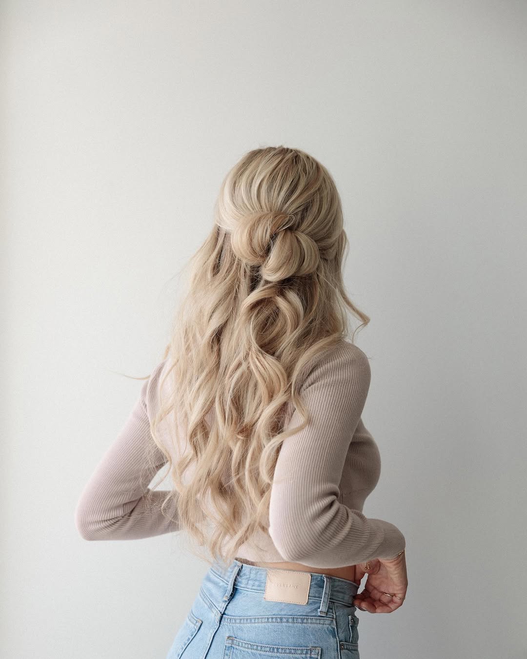 A woman with soft waves in her hair styled in a twisted half-up do.