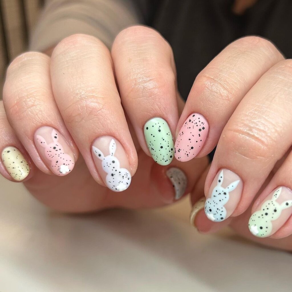 Pastel nails with speckled textures and cute bunny face designs.