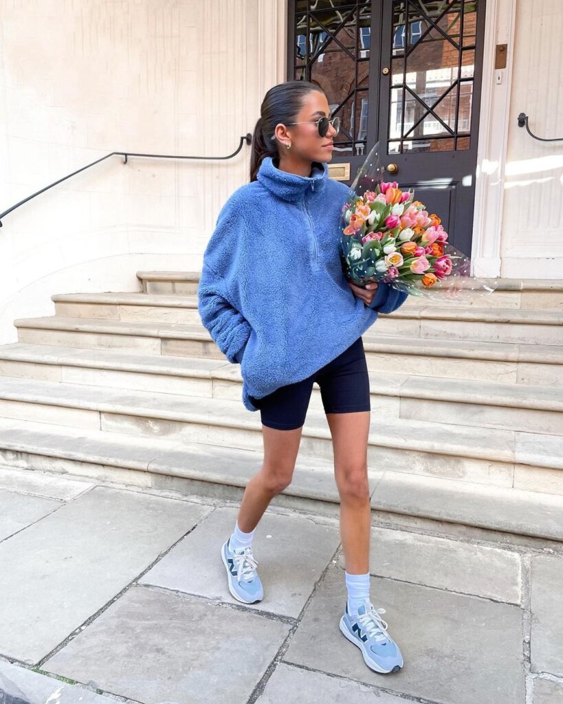 An oversized fleece jacket worn with biker shorts offers a balance of comfort and style for active spring days.