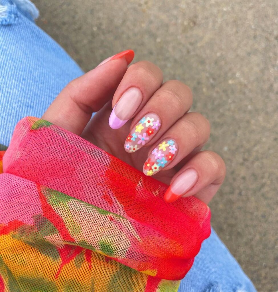 Coral-toned French tips with tiny multicolor floral details on a sheer base.