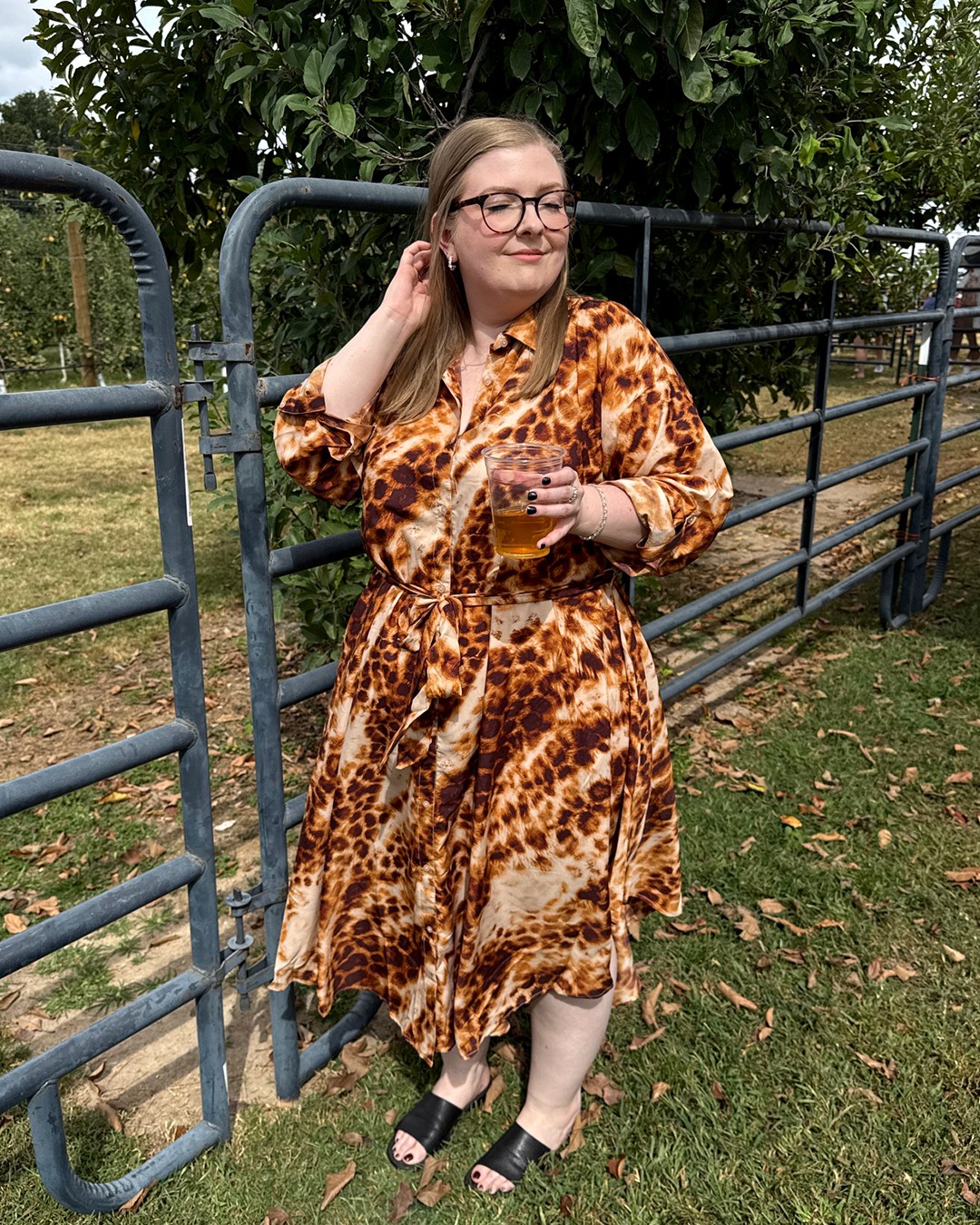A woman in a midi dress with an animal print pattern and a cinched waist.