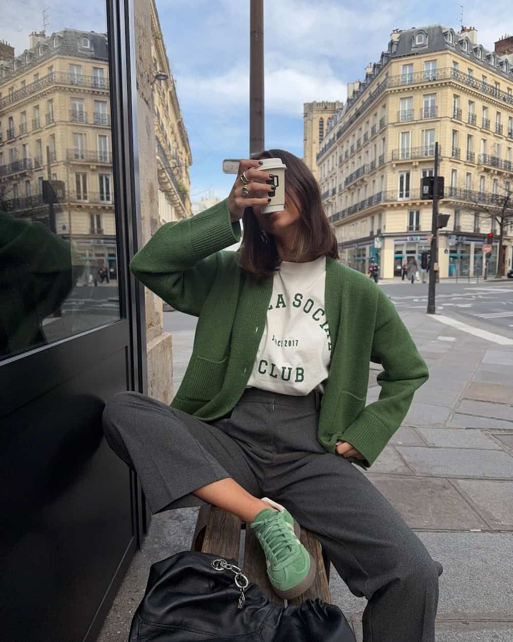 Woman wearing slacks, graphic tee, and a green cardigan with matching sneakers