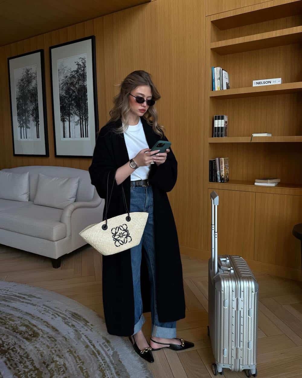 Woman wearing blue jeans, white t-shirt, black coat, and slingback flats