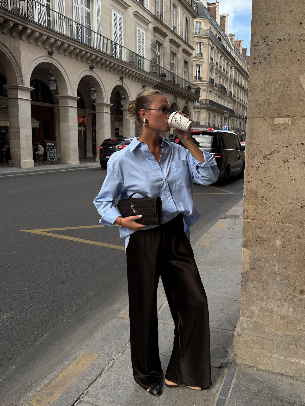Woman wearing black silk trousers and a baby blue button-up shirt