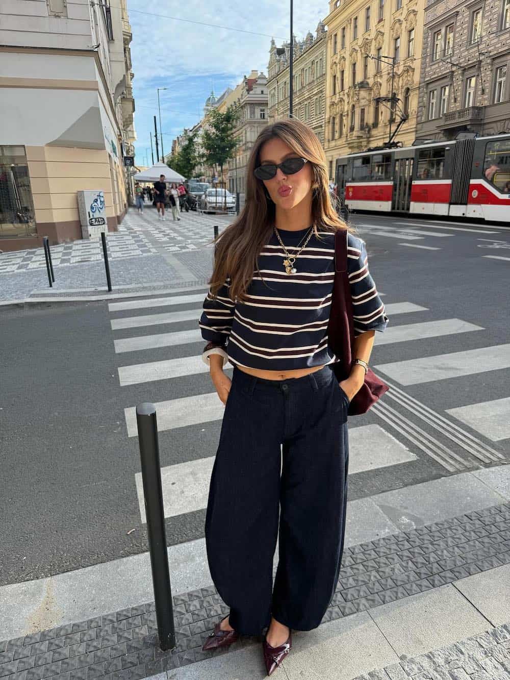 Woman wearing dark barrel jeans, striped tee, and ballet flats