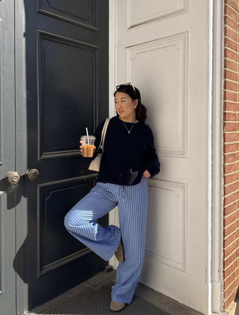 Woman wearing striped pants, a sweater, and suede clogs