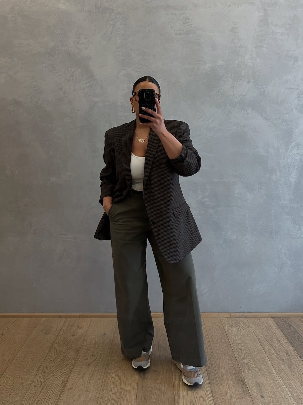 Woman wearing wide-leg pants, a simple top, and a patterned blazer with sneakers