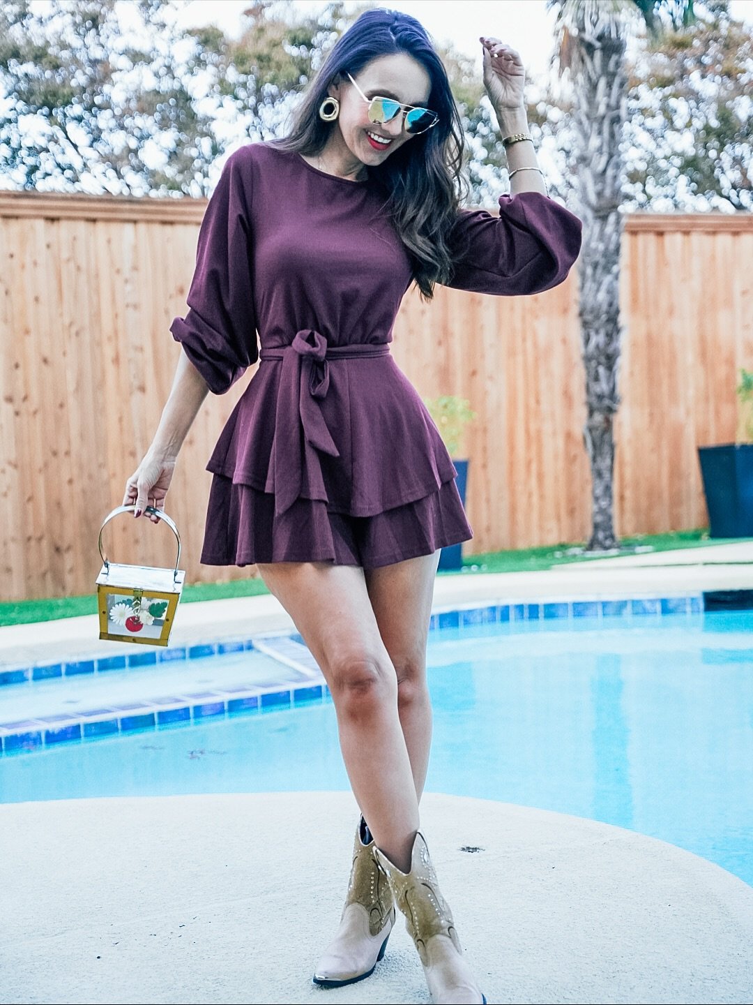 A deep berry long-sleeved mini dress with balloon sleeves and a cinched waist, styled with sunglasses and ankle boots.