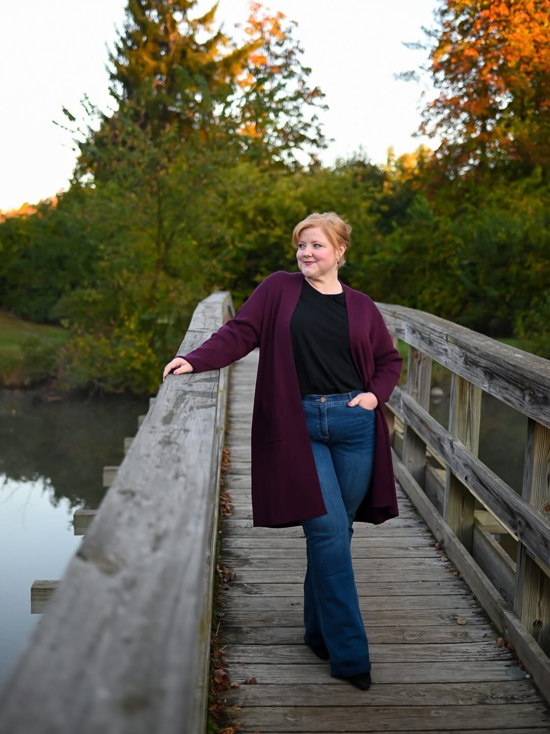 A long-sleeved burgundy cardigan layered over a simple top with flared jeans.