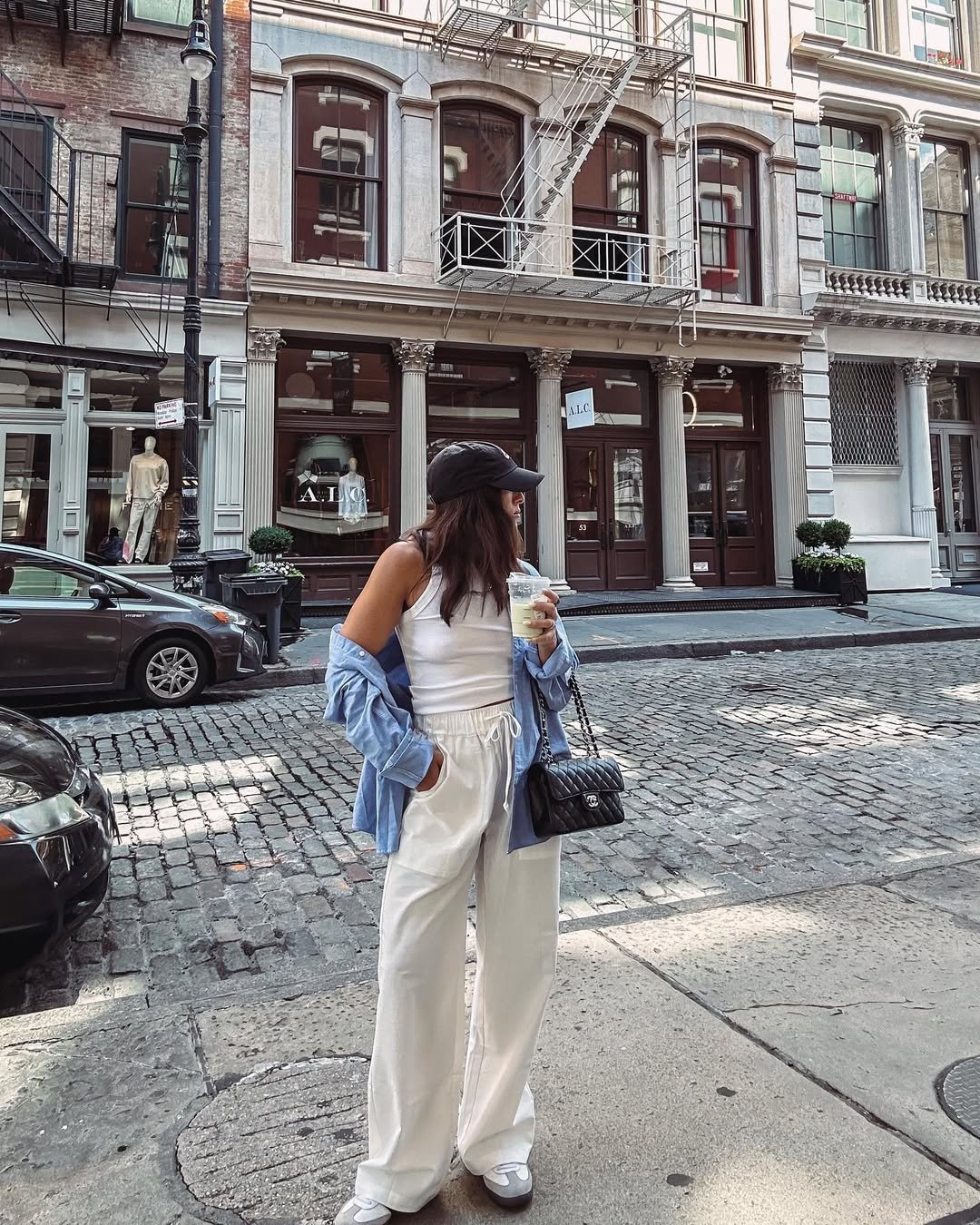 Woman wearing relaxed drawstring linen pants, a fitted tank, and a blue shirt.