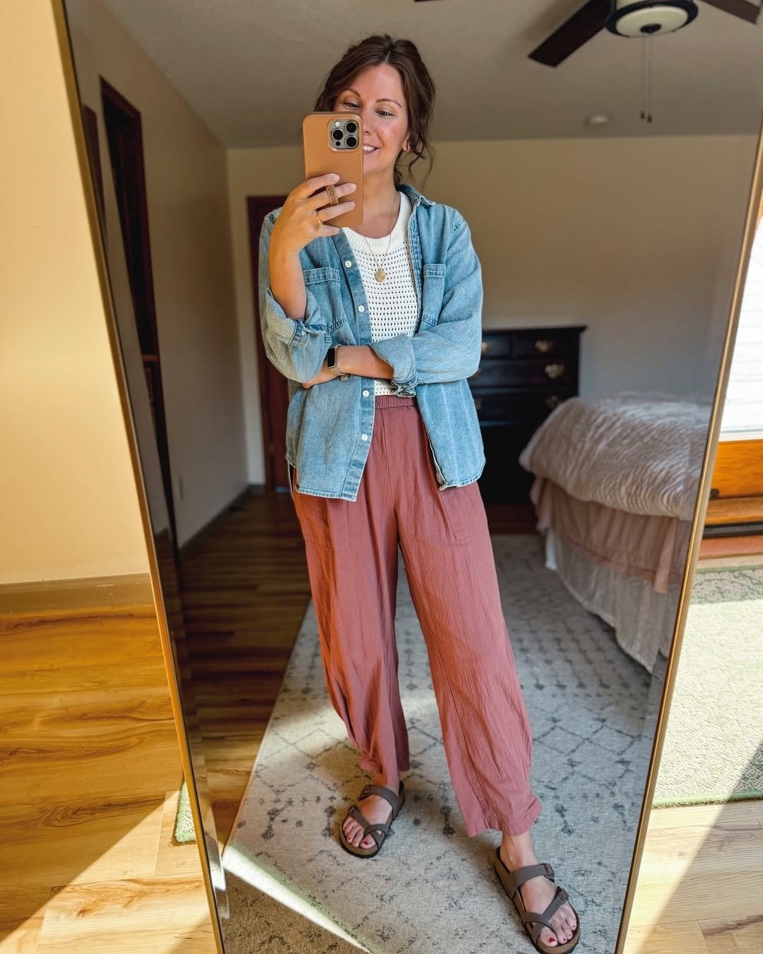 Woman wearing dusty rose linen pants with a lightweight knit and an open chambray shirt.