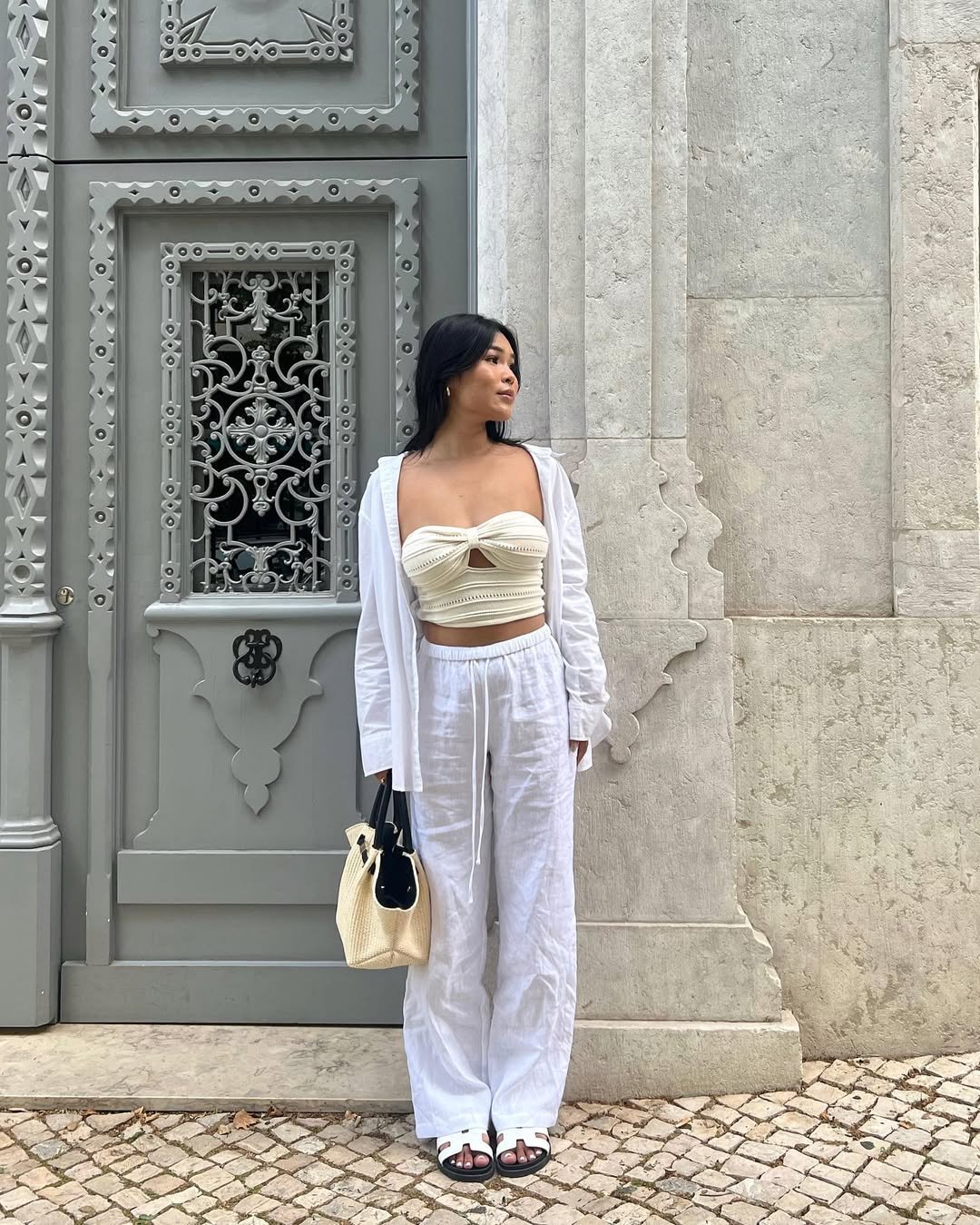 Woman wearing cream bandeau, white linen pants, and an open white button-down shirt.