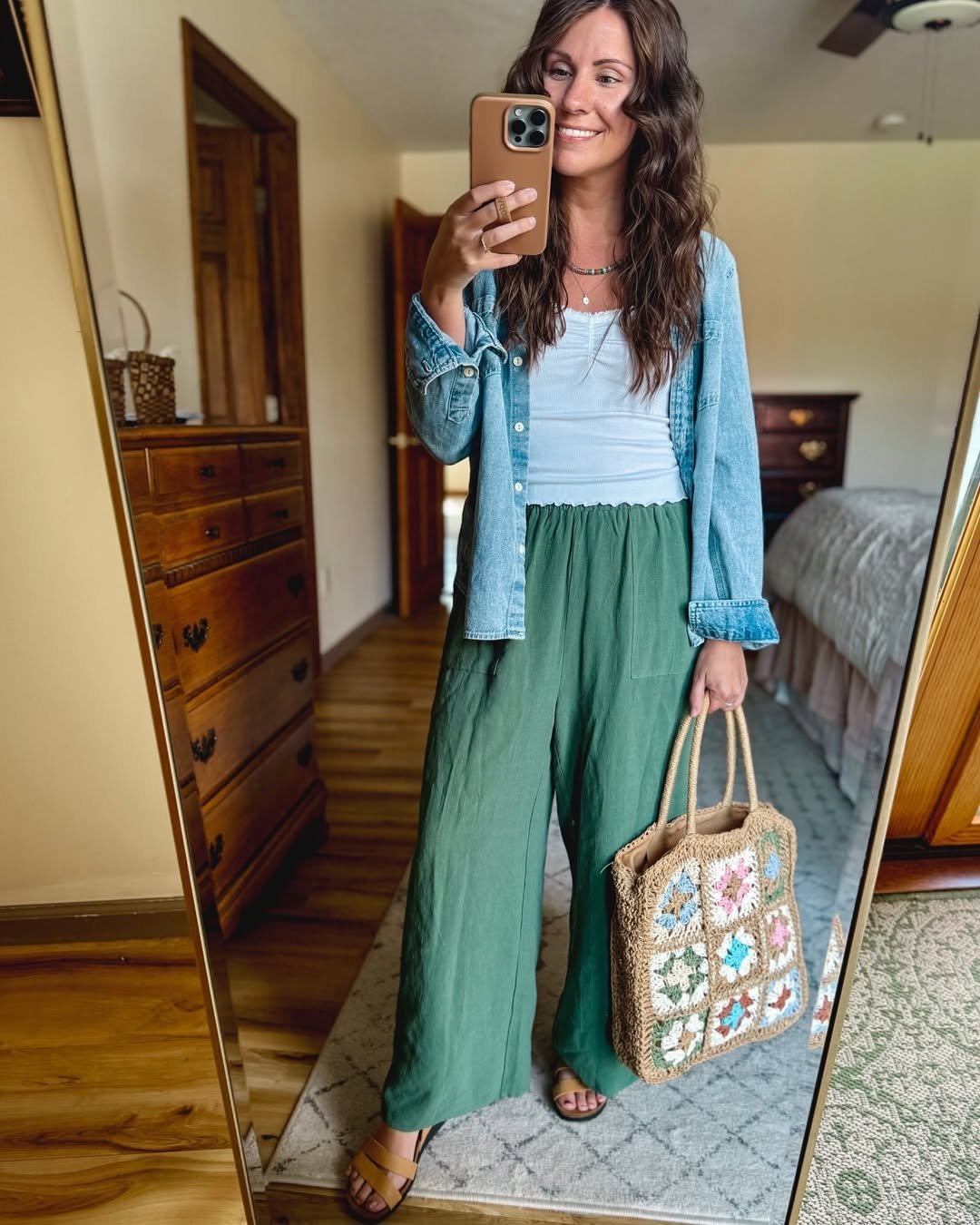 Woman wearing sage green linen pants with a ribbed tank and a chambray shirt.