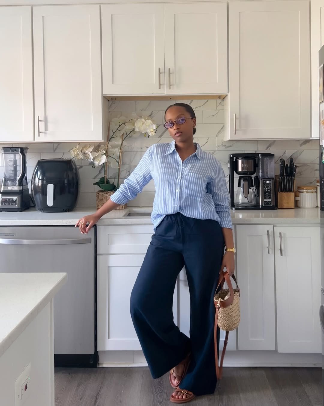 Woman wearing navy wide-leg linen pants with a blue striped button-down shirt.