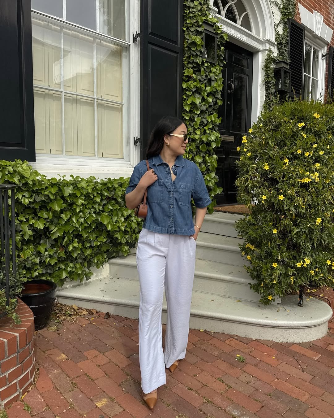 Woman wearing fluid white linen pants with a cropped denim button-down and pointed-toe flats.