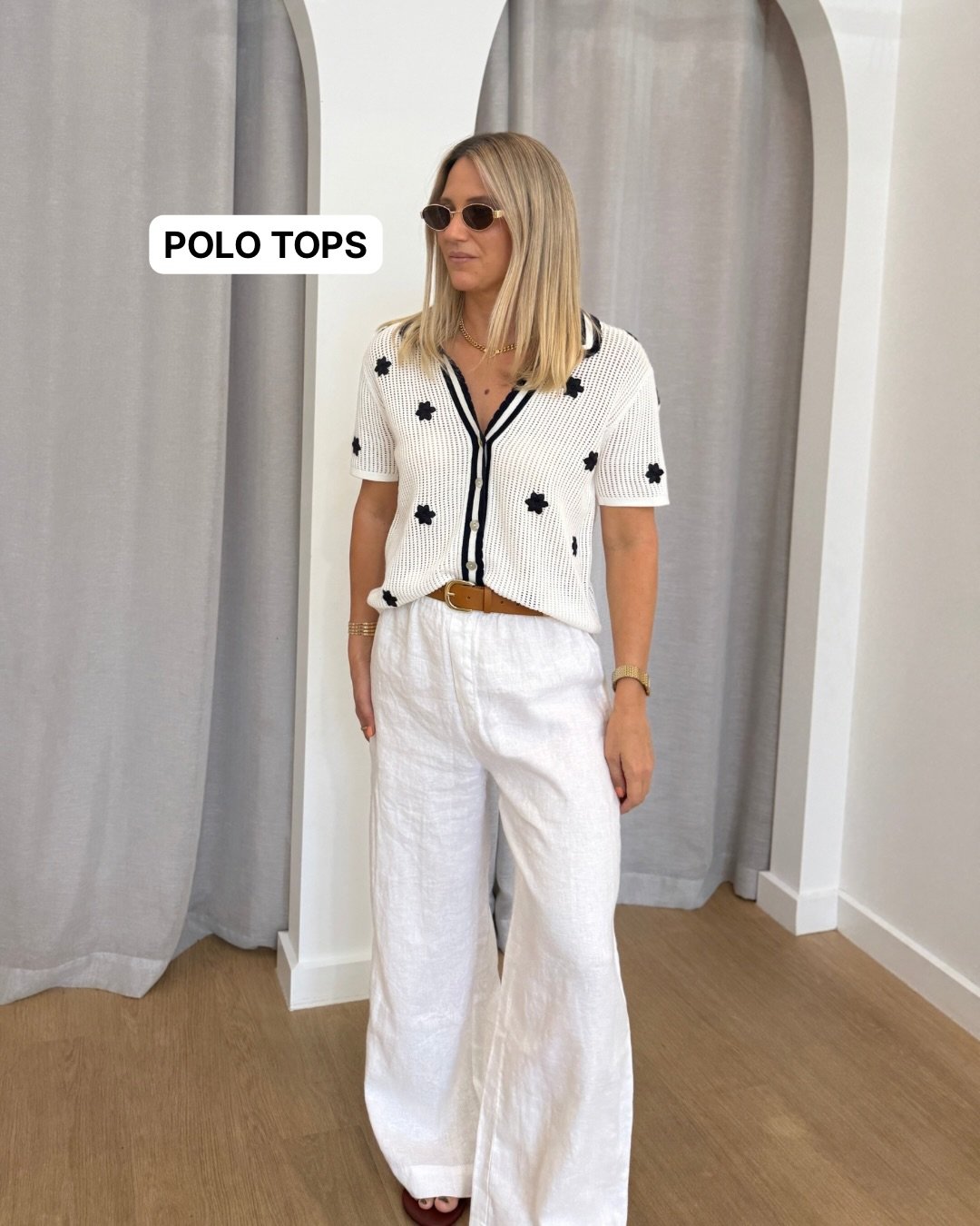 Woman wearing white linen pants with a knit polo shirt and belt.
