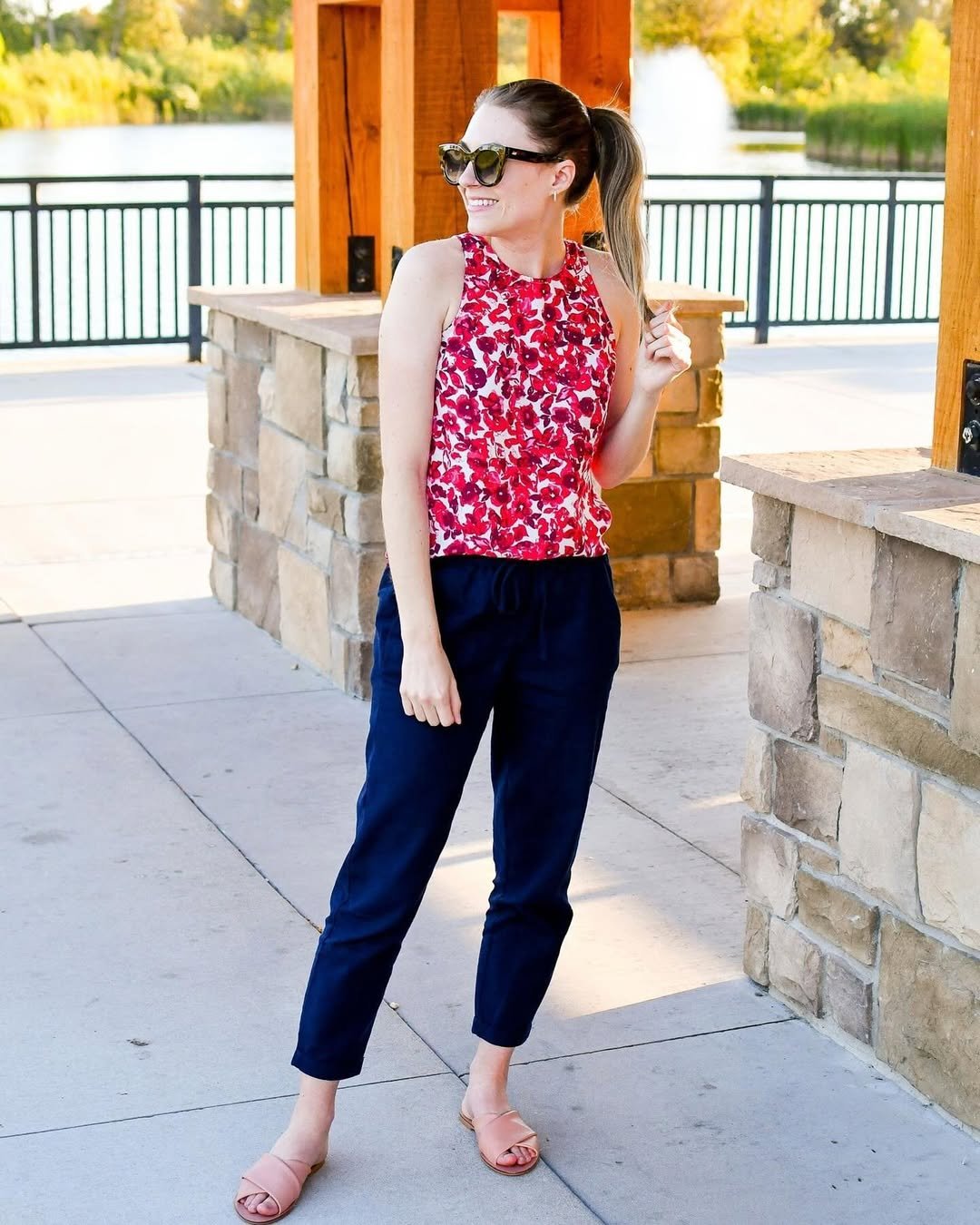 Woman wearing navy linen pants with a red floral halter top.