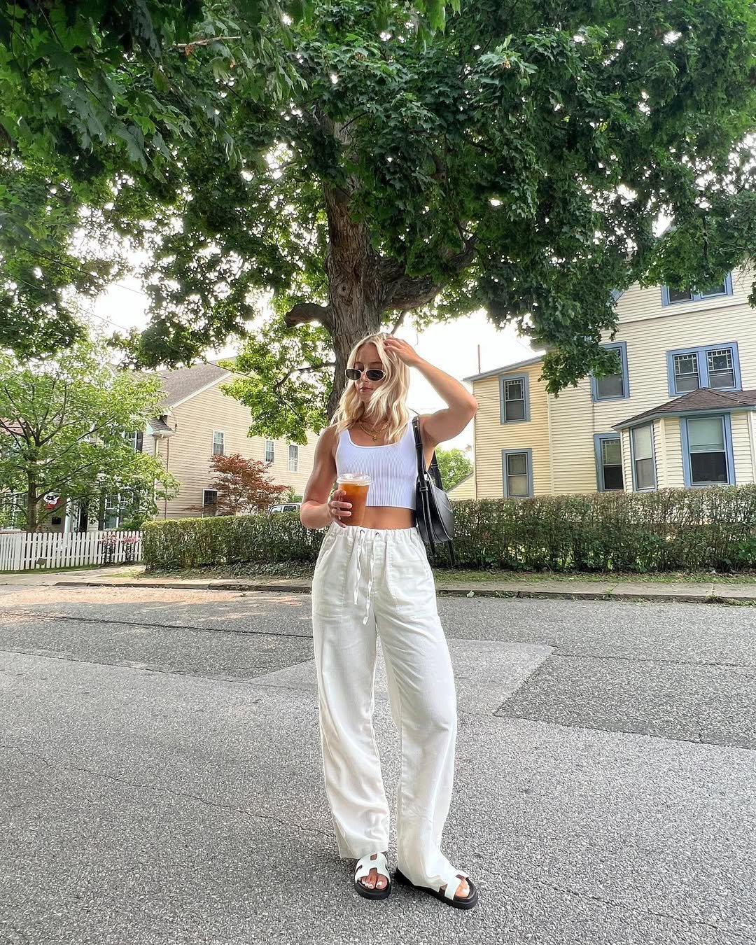 Woman wearing white linen pants with a fitted white crop top and chunky sandals.