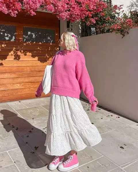 Woman in pink sweater and floral skirt with pink Converse