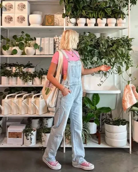 Woman in baby blue overalls and pink tee at a plant shop