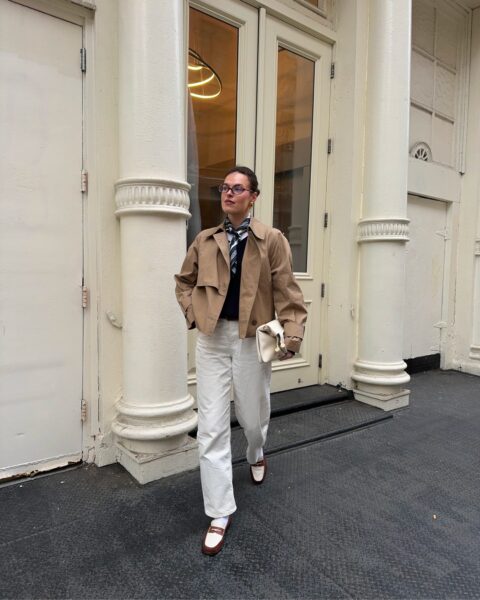 Camel trench coat, navy tie, and ivory trousers.