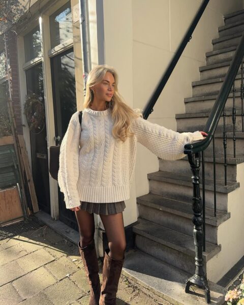 Cable-knit sweater, pleated mini skirt, and suede boots.