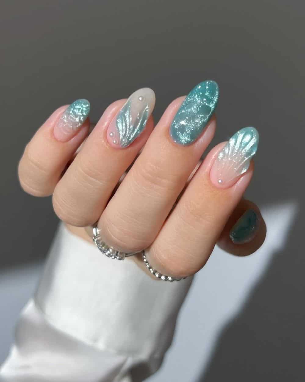 Ocean-textured teal nails with 3D seashell art