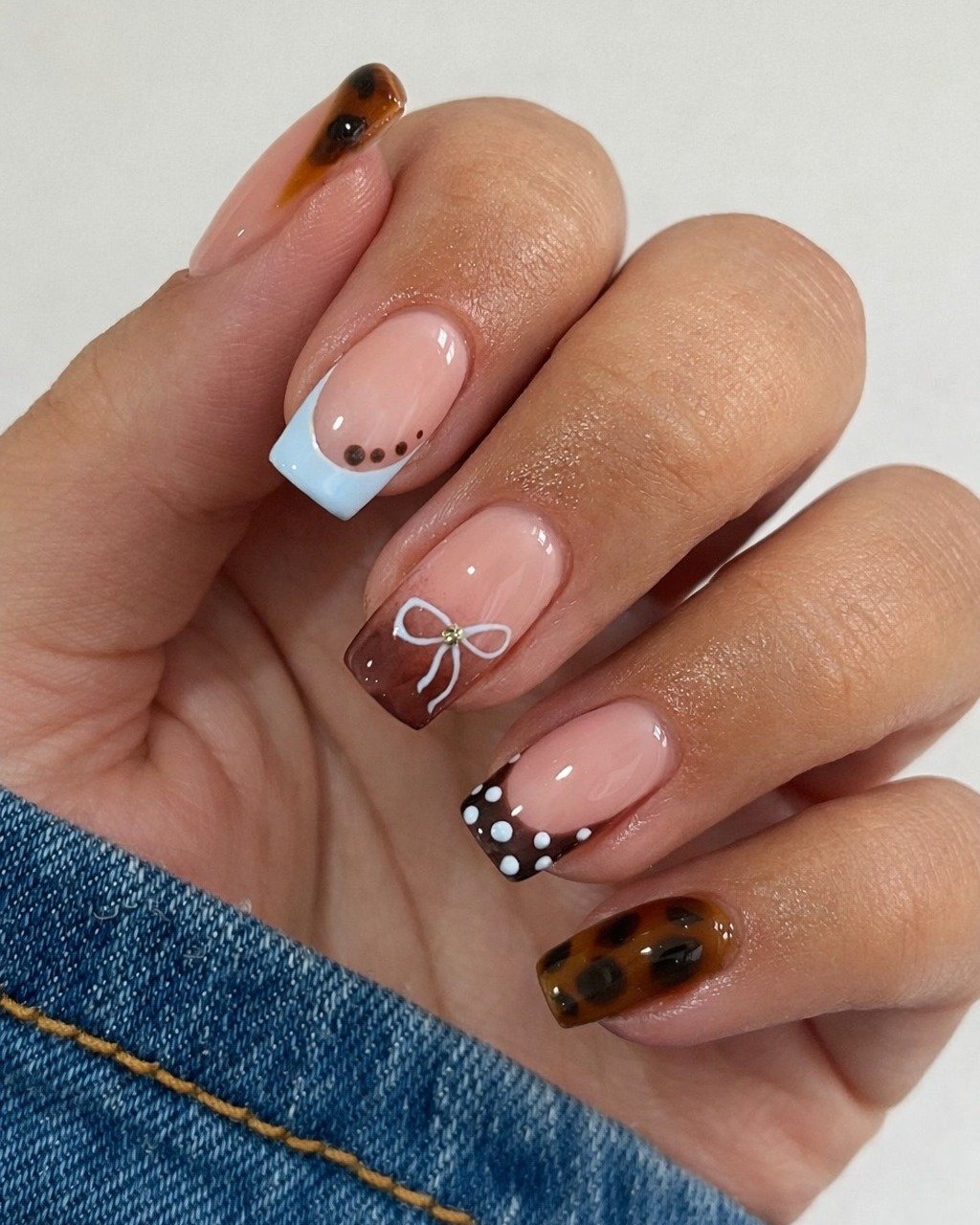 Nails with varied designs including tortoiseshell, polka dots, and bows