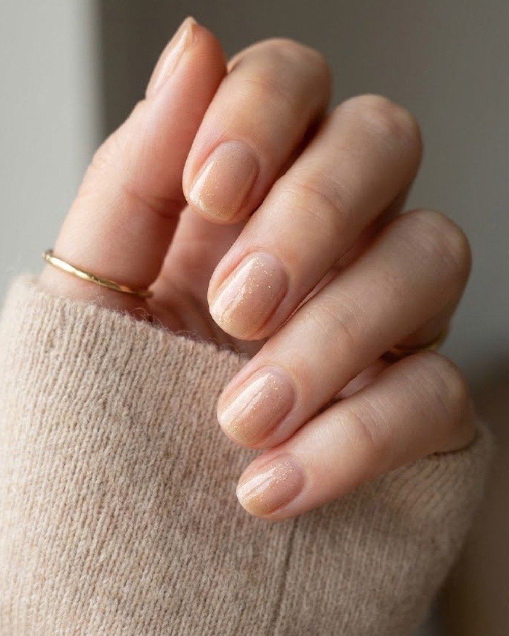Nude nails with a sheer finish and fine glitter for a subtle sparkle